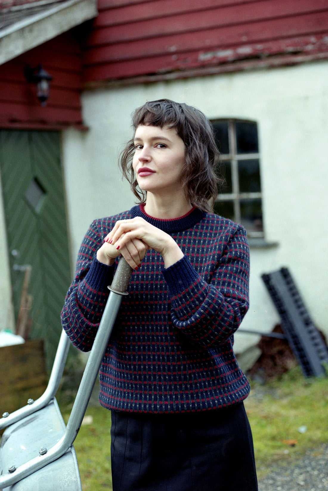 Woman holding a shovel in front of a rustic building