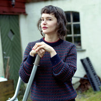 Woman holding a shovel in front of a rustic building