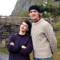 Two people standing outdoors with a scenic background of mountains and trees.