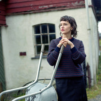 Woman holding a metal railing in front of a building with red roof