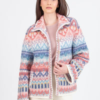 Woman wearing a colorful patterned jacket and white pants on a white background