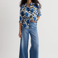 Woman wearing a floral blouse and blue jeans on a white background