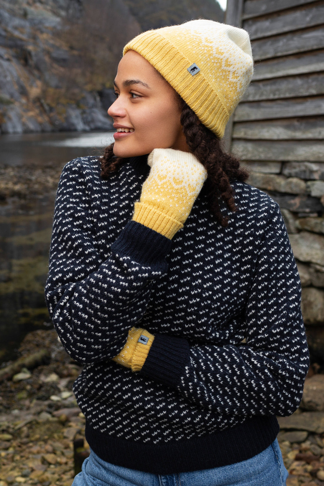 Model wears the Snow Storm Beanie in Yellow in front of a lake.