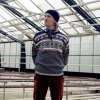 Person wearing a patterned sweater and beanie standing inside a large industrial building.
