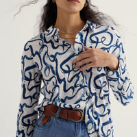 Woman wearing a blue and white patterned shirt with blue jeans on a white background