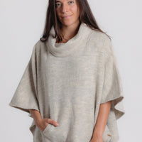 Woman wearing a beige poncho against a white background