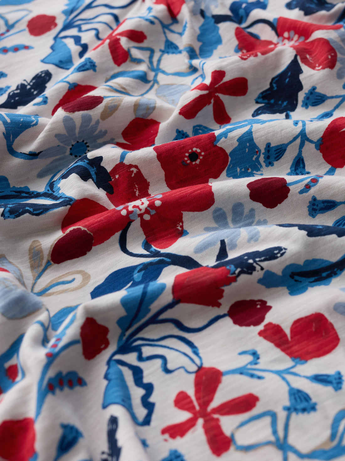 Close-up of floral fabric with red, blue, and white flowers on a white background