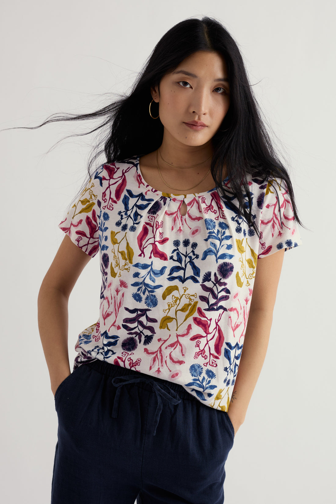 Woman wearing a colorful floral-patterned shirt against a white background