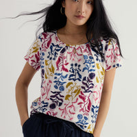 Woman wearing a colorful floral-patterned shirt against a white background