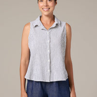 Woman wearing a sleeveless striped shirt and blue pants against a beige background
