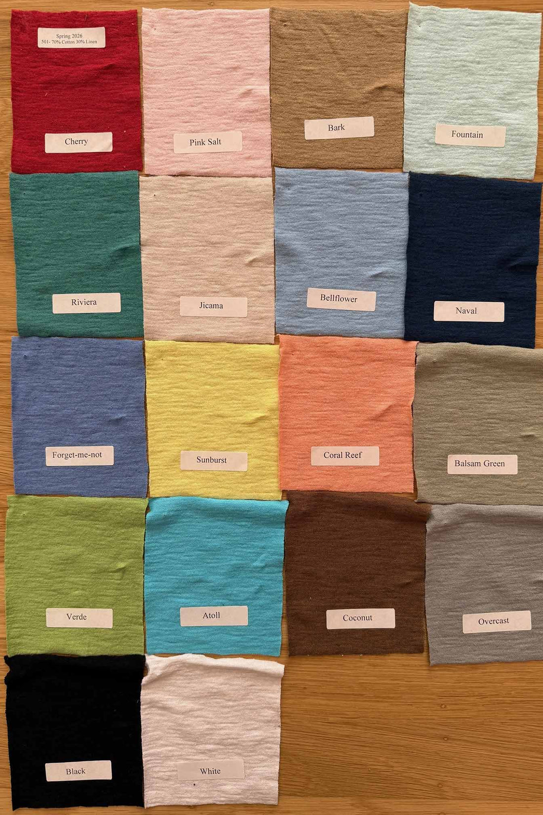 Collection of colorful fabric swatches arranged in a grid on a wooden surface.