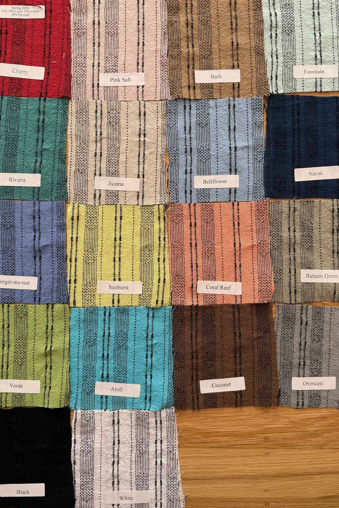 Fabric swatches in various colors arranged in a grid on a wooden surface.