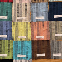 Fabric swatches in various colors arranged in a grid on a wooden surface.