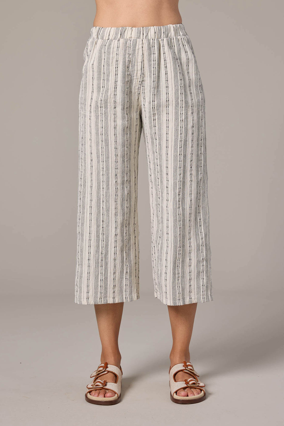Person wearing white and gray striped pants on a plain background