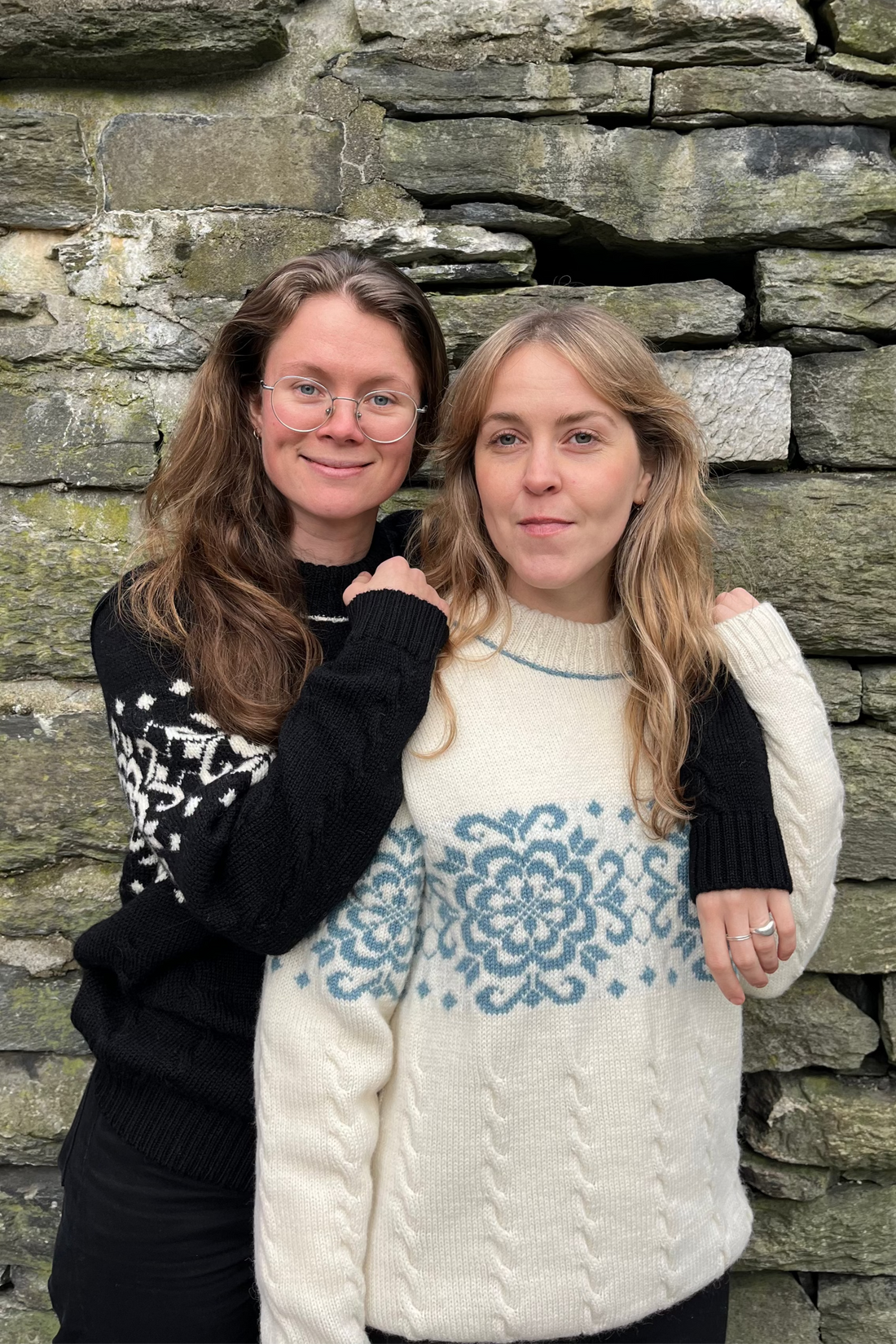 Two women standing in front of a stone wall