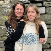 Two women standing in front of a stone wall
