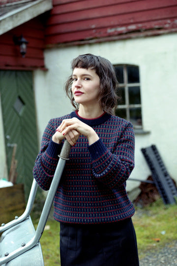 Woman holding a shovel in front of a rustic building