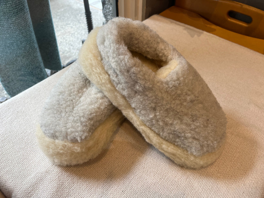 light grey wool slippers on a neutral background.