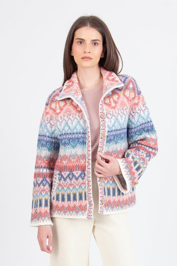 Woman wearing a colorful patterned jacket and white pants on a white background