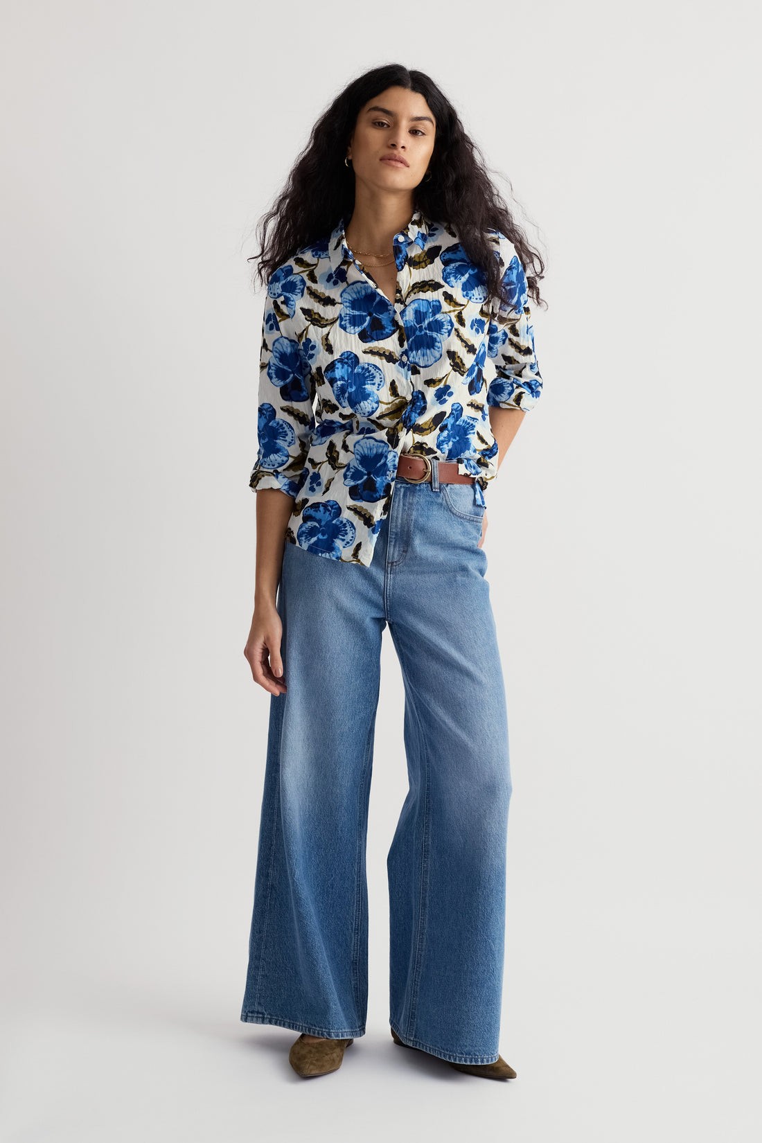 Woman wearing a floral blouse and blue jeans on a white background