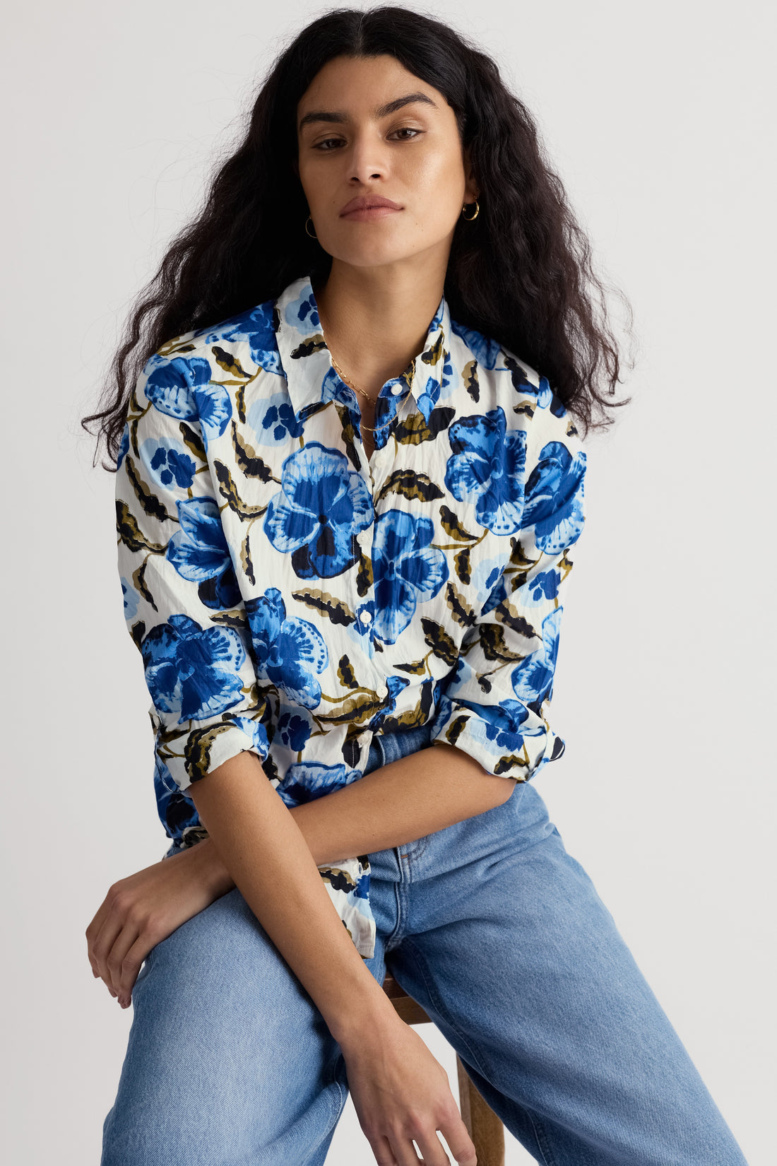 Woman wearing a floral shirt with blue flowers and jeans on a white background