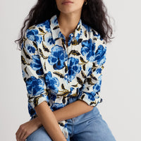 Woman wearing a floral shirt with blue flowers and jeans on a white background