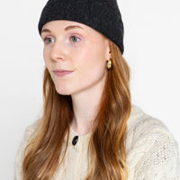 A person wearing a black beanie hat made from alpaca wool.