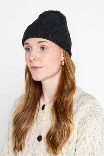 A person wearing a black beanie hat made from alpaca wool.