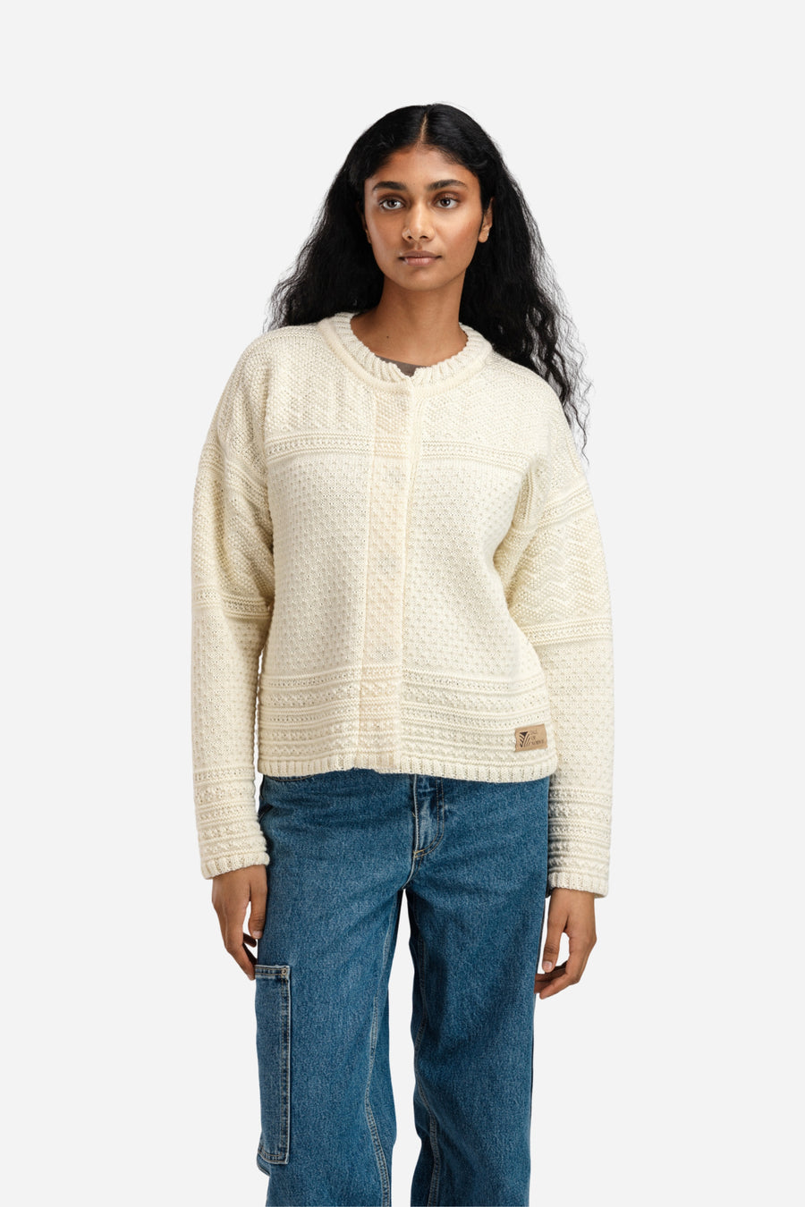 Woman wearing a cream sweater and blue jeans on a white background