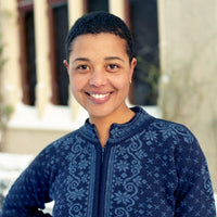 Person wearing a blue patterned sweater standing outdoors with a building in the background