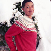 Person wearing a red sweater with a patterned yoke standing outdoors with snow and trees in the background
