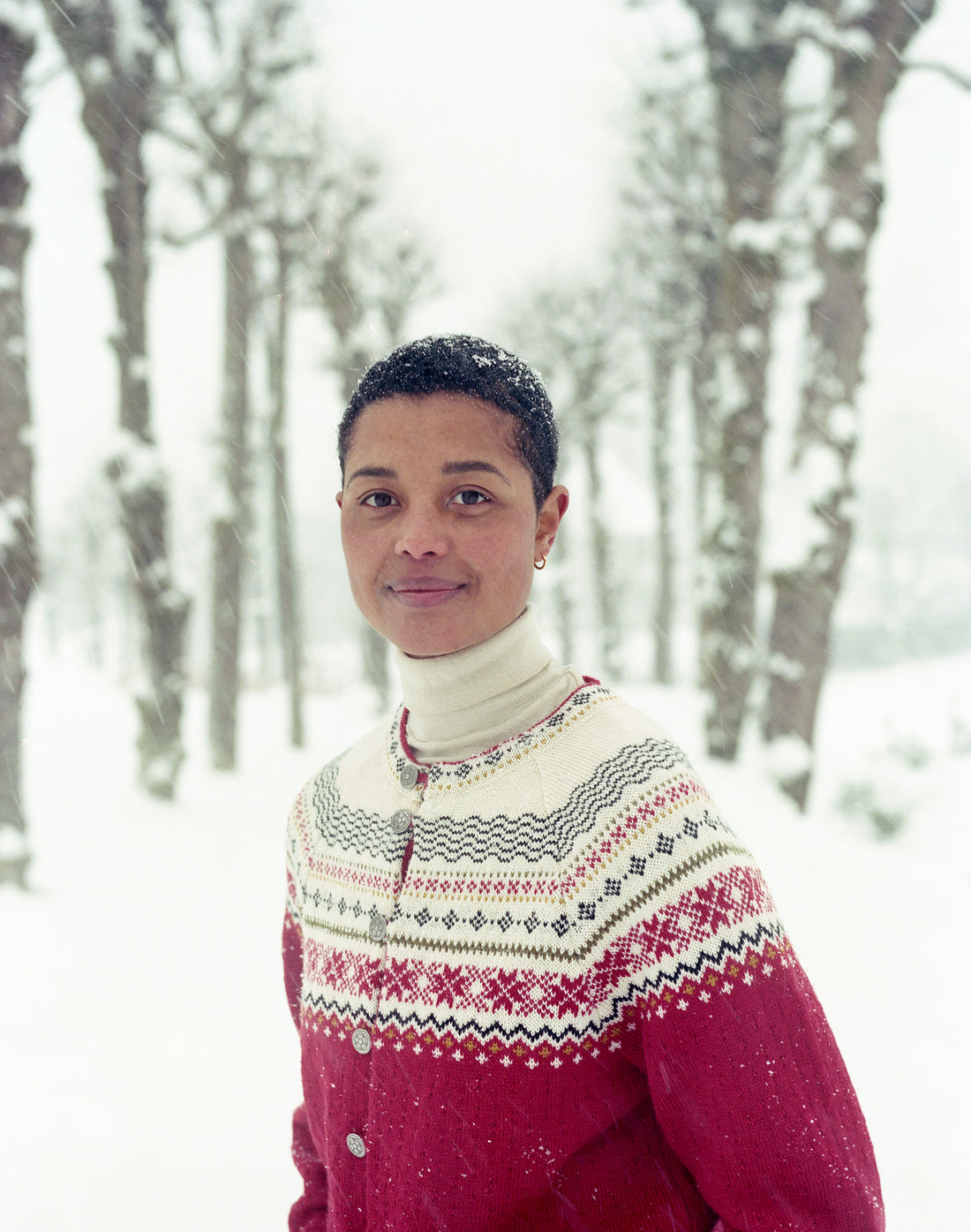 Person wearing a pink and white patterned sweater in a snowy forest