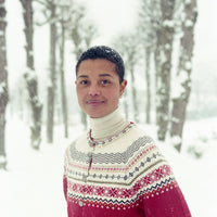 Person wearing a pink and white patterned sweater in a snowy forest