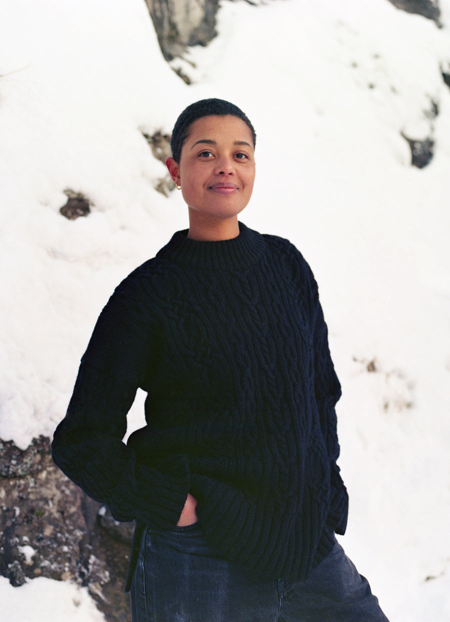 Person wearing a black sweater standing in a snowy landscape