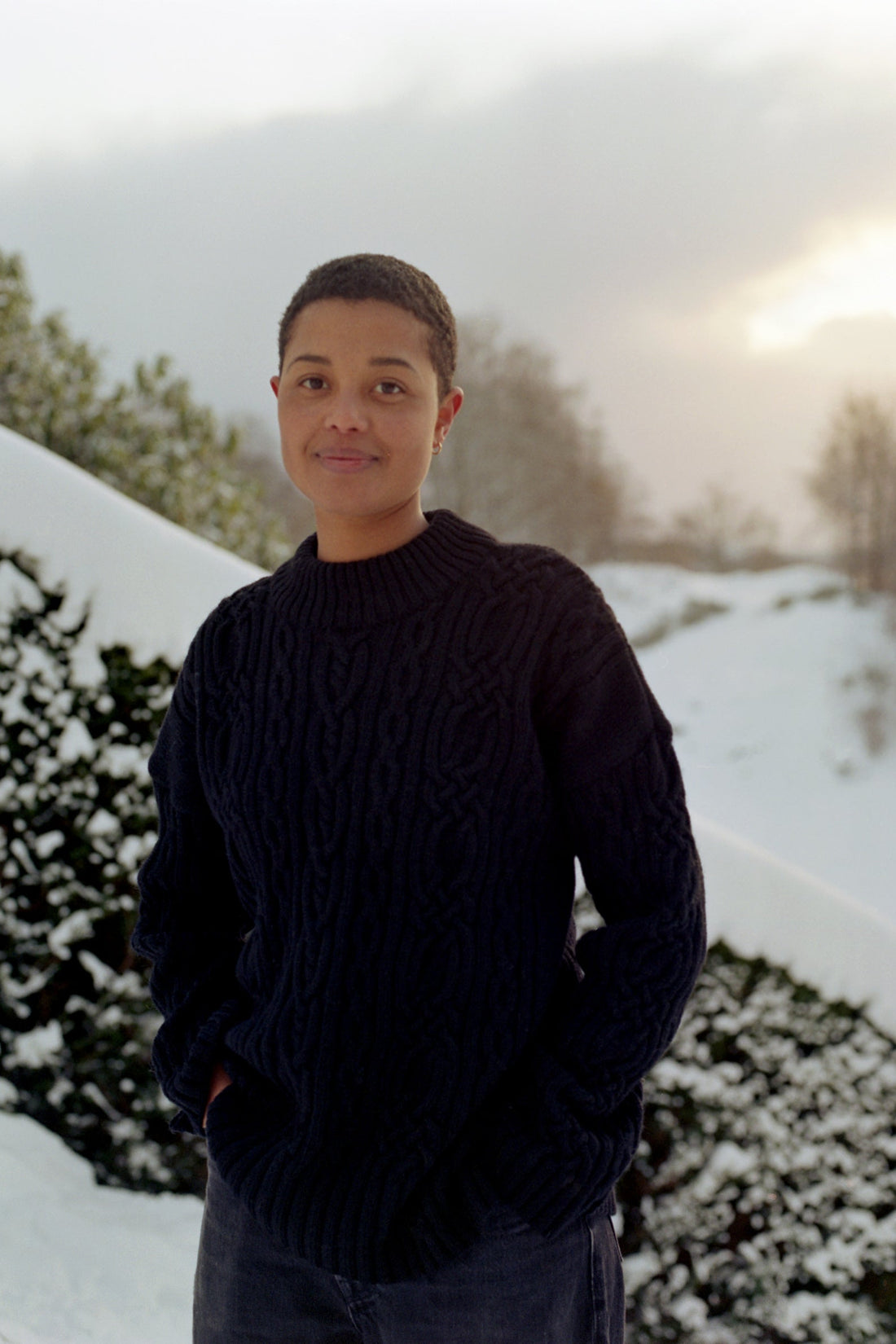 Person wearing a dark sweater standing in a snowy landscape
