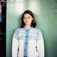 Person wearing a patterned sweater against a green wall