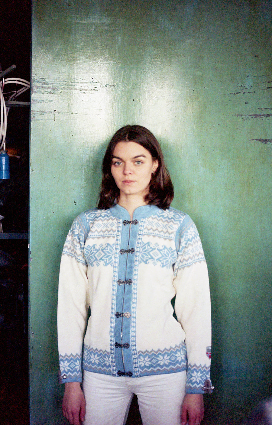 Person wearing a patterned sweater against a green wall