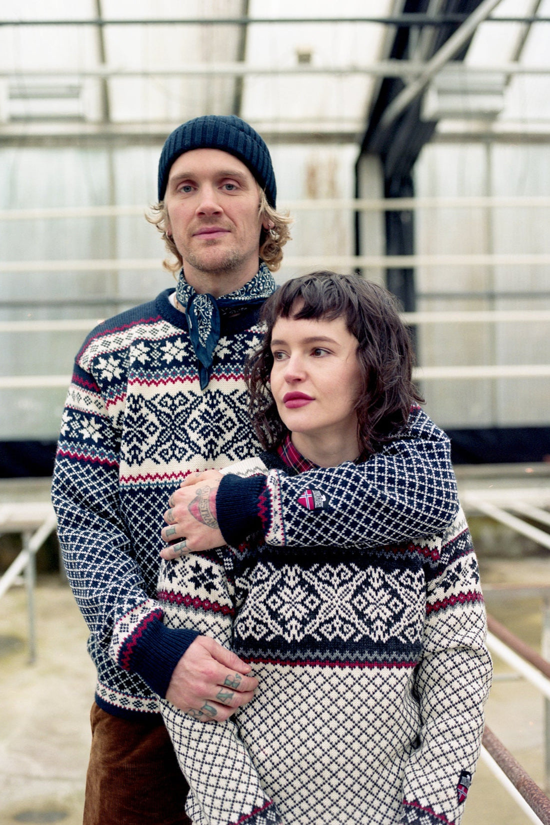 Two people wearing matching patterned sweaters in an indoor setting.