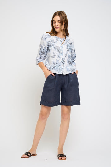 Woman wearing a floral blouse and navy shorts on a white background