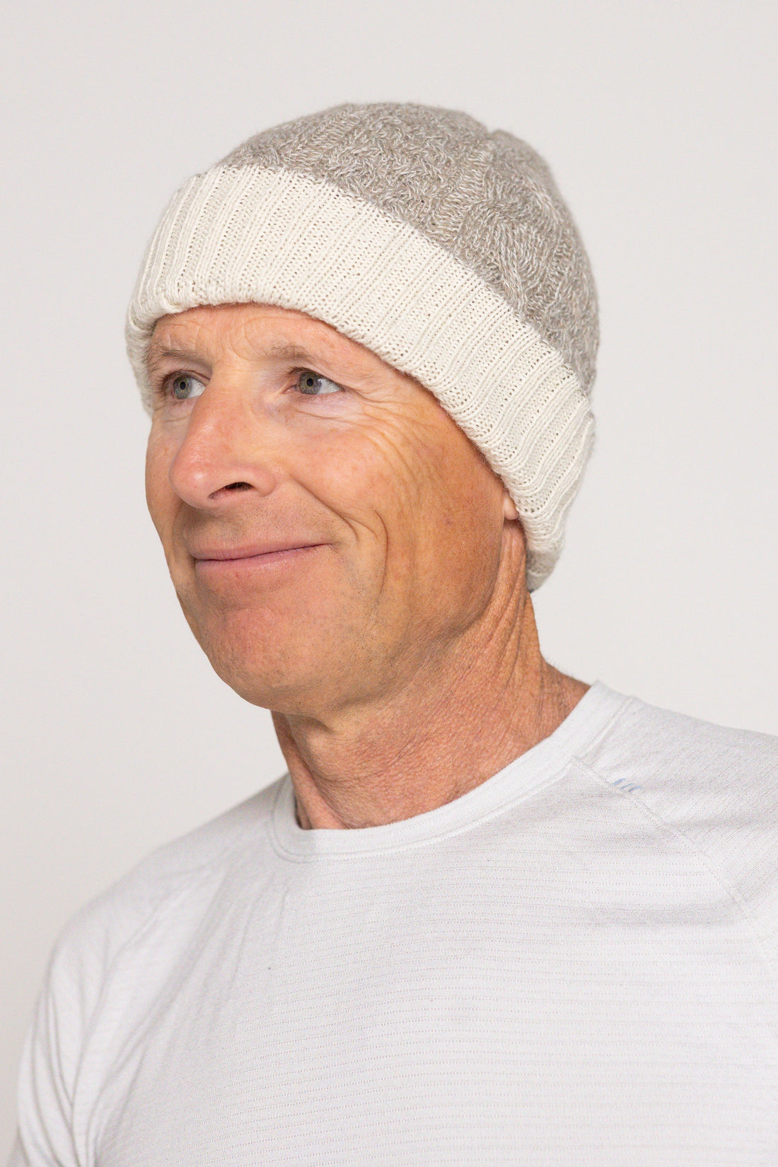 Man wearing a white knit beanie against a plain background