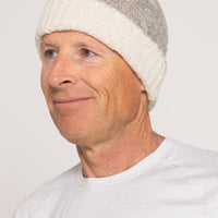 Man wearing a white knit beanie against a plain background