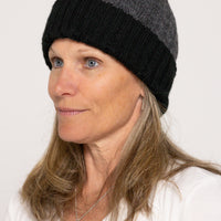 Woman wearing a black and gray beanie against a white background