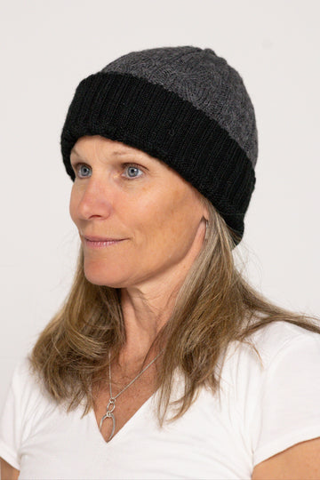 Woman wearing a black and gray beanie against a white background