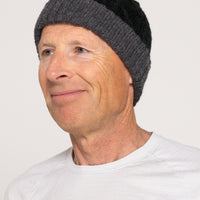 Man wearing a gray knit beanie against a white background