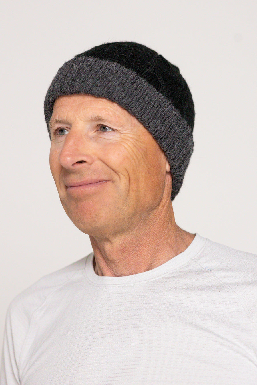 Man wearing a gray knit beanie against a white background