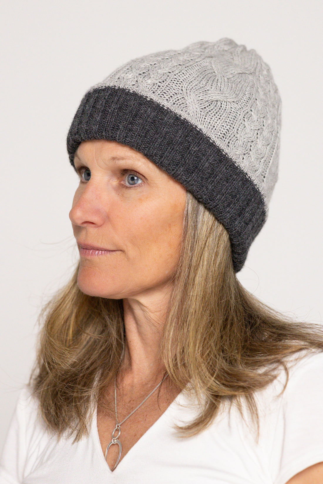 Woman wearing a gray knit beanie with a white background
