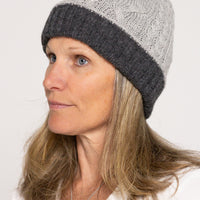 Woman wearing a gray knit beanie with a white background