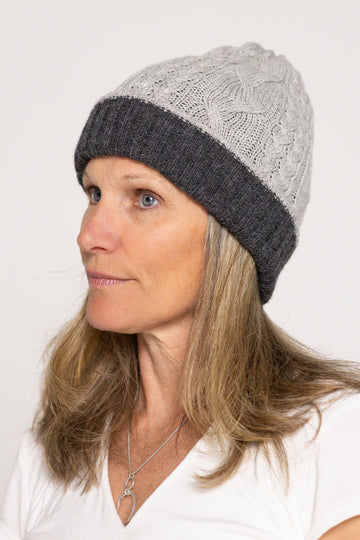 Woman wearing a gray knit beanie with a white background