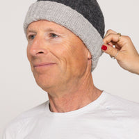 Person wearing a gray knit beanie with a plain background