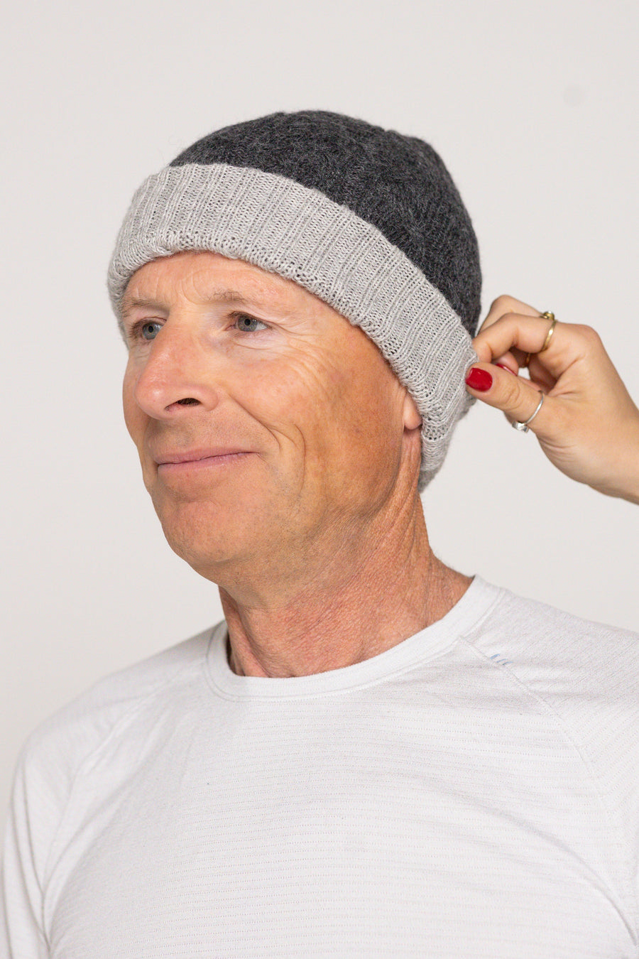 Person wearing a gray knit beanie with a plain background
